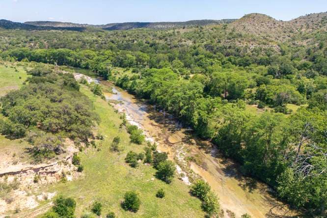 The Blanco River valley from the air, the river winding between wooded hills