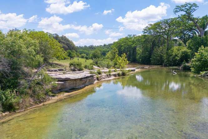 The Blanco River below a low limestone bluff and live oaks