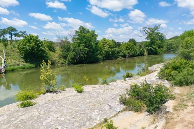 The Blanco River seen from a limestone shelf, with cedar and live oaks on the far bank