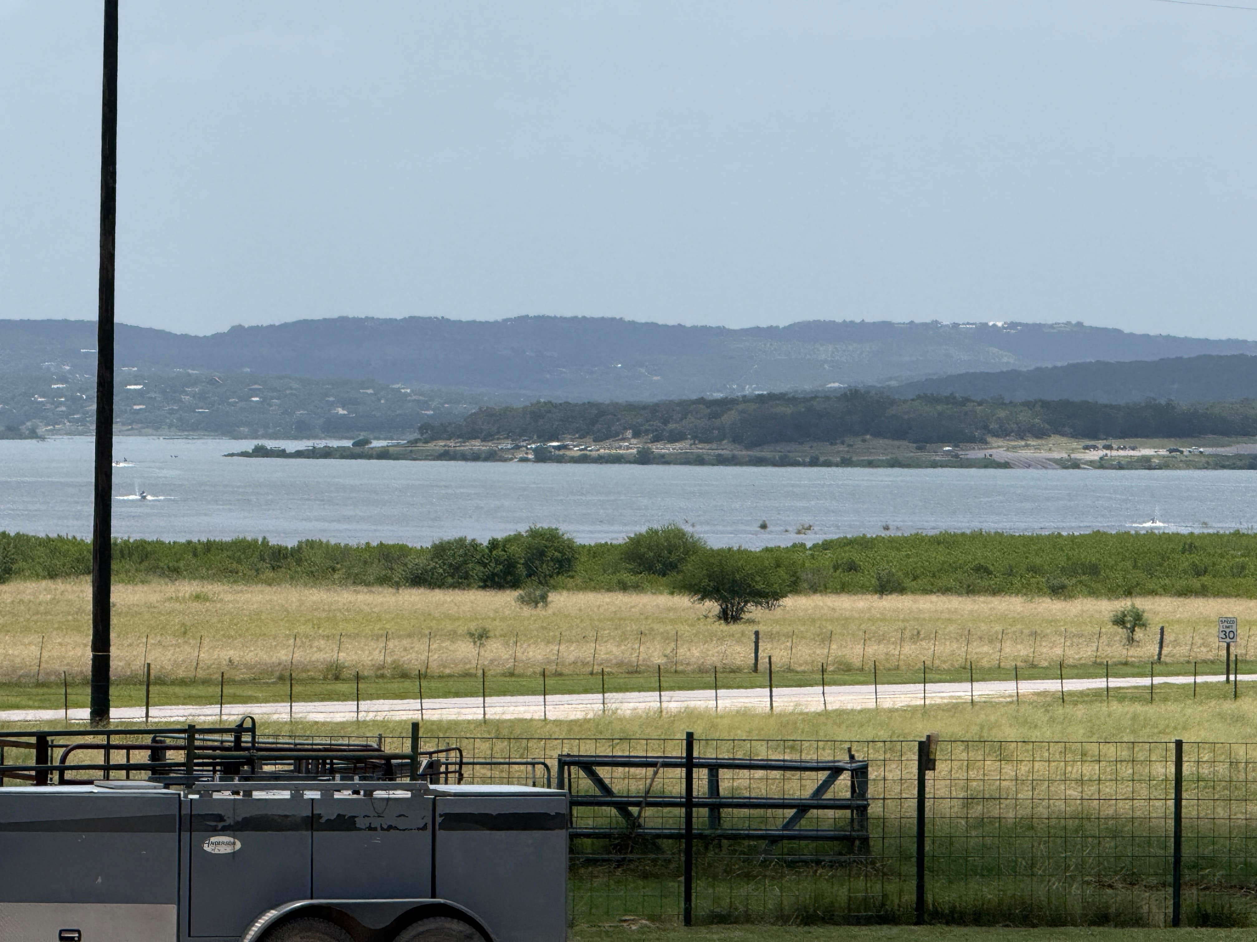 Canyon Lake seen across a fenced pasture, with the hills on the far shore